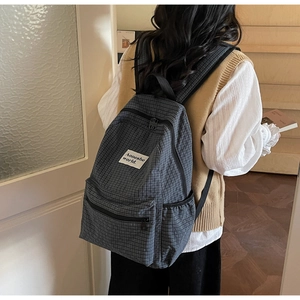 Close-up of a plaid pattern backpack with a white fabric label and multiple storage pockets