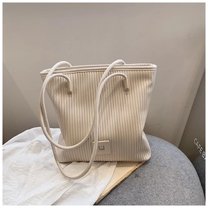 Dettaglio della borsa tote beige con trama a pieghe verticali e fibbia decorativa quadrata