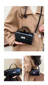Detail of black minimalist leather handbag with silver metallic turn-lock and fine strap