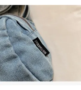 Dettaglio della trama in denim azzurro e dell'etichetta tessuta nera di una borsa casual