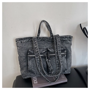 Detail of washed dark grey denim tote bag with dual zipper pockets and worn texture