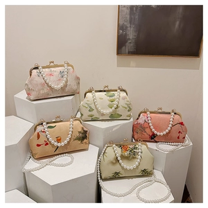 Detailed display of five embroidered floral handbags with pearl handles and chain straps