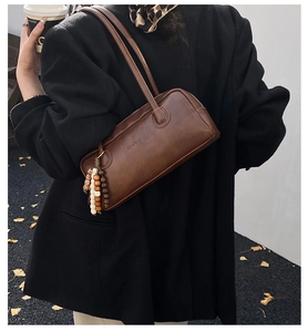 Close-up of brown leather underarm bag featuring decorative beads and embossed chic logo