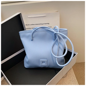 Dettaglio macro del tessuto a pieghe verticali sulla borsa tote azzurra con confezione
