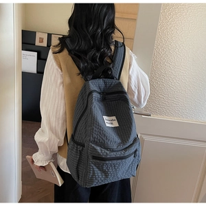 Detail view of the gray plaid backpack showing its spacious main pocket and minimalist design