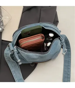 Internal view of blue denim crossbody bag showing large capacity for phone and wallet