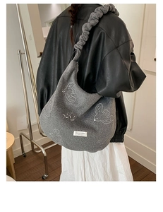 Detail of grey felt tote bag featuring white bird embroidery and scrunchie shoulder strap