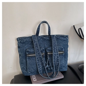 Close-up of deep blue washed denim tote bag with functional zipper pockets and straps