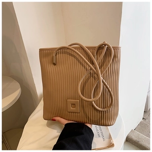 Dettaglio della borsa tote a pieghe color cammello con trama verticale e tracolla in pelle
