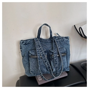 Detail view of washed denim tote bag with functional front zip pockets and dual straps