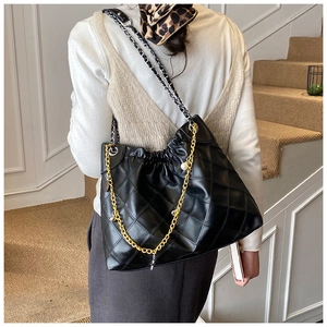 Detail of quilted black tote bag with pearl chain strap and drawstring closure