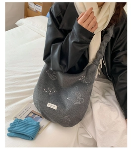 Detailed view of grey felt hobo bag featuring floral embroidery and braided shoulder strap