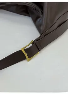 Detail of dark coffee leather tote showing gold metal adjustable buckle on shoulder strap