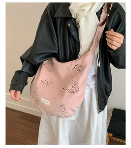 Detail of pink canvas tote bag showing artistic bird and floral patterns with white logo tag