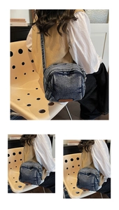 Dettaglio borsa a tracolla in denim blu lavato con cerniere multiple e toppa in pelle