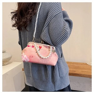 Close-up of pink floral shell bag with pearl strap and vintage metal clasp closure