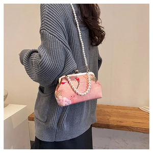 Detail view of the pink floral embroidery handbag with elegant pearl strap and metal clasp