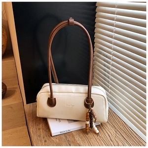 Detail of cream PU leather shoulder bag with dark brown strap and colorful beaded charm
