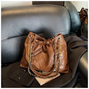 Detail of coffee brown quilted cloud bag featuring dual-tone gold and silver chain strap