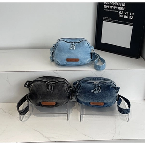 Detailed stack of vintage denim crossbody bags in light blue, dark blue, and charcoal grey