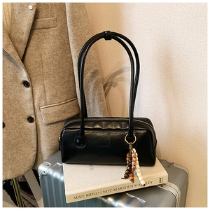 Close-up of black leather underarm bag featuring decorative beads and silver zipper detail