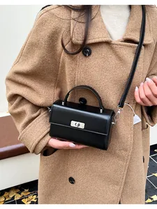 Detail view of a black leather crossbody bag with silver twist lock and handle on wool coat