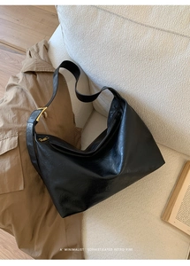 Detail shot of vintage black hobo bag with oily leather texture and golden metal hardware