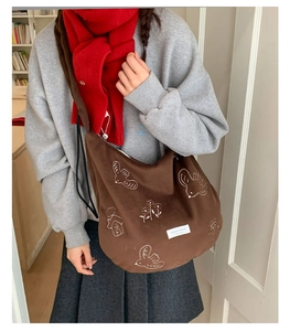 Close-up of white embroidery on dark brown canvas tote bag with bird and flower patterns