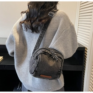 Dettaglio borsa a tracolla in denim grigio con strati a zip e toppa logo in pelle