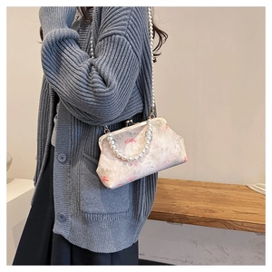 Detail of vintage floral embroidery purse with elegant pearl chain strap on model