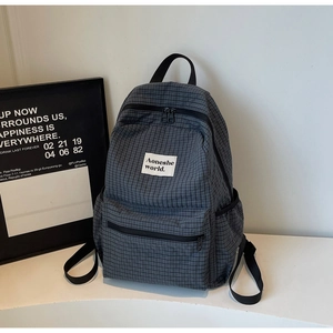 Detail view of the gray plaid backpack showing the side pocket and adjustable straps