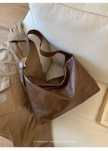 Deep brown retro faux leather hobo bag with gold buckle displayed on a cozy sofa