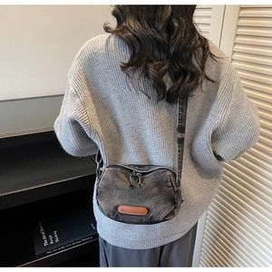 Detailed view of a retro washed denim crossbody bag with a brown leather logo patch