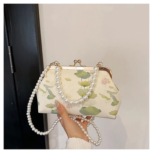 Close-up of vintage lotus embroidery fabric and pearl handle on a Chinese qipao bag