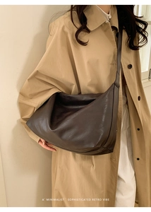Deep brown large capacity tote bag shown cross-body on a trench coat model