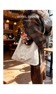 Detail of minimalist tote bag with soft suede texture and festive bear charm accessory
