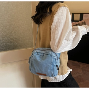 Dettaglio della borsa a tracolla in denim azzurro con etichetta in pelle e zip