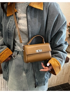 Close-up of brown synthetic leather handbag with silver twist lock and metal buckle