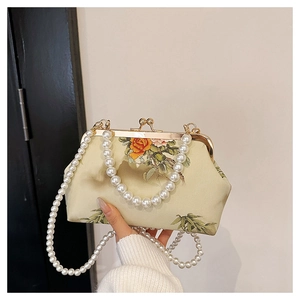Detailed macro view of vintage silk evening bag with floral motifs and pearl chain handle