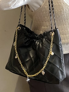 Minimalist black quilted leather tote bag with elegant gold chain and charm details