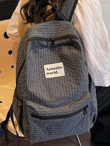 Minimalist dark grey plaid backpack with brand patch and front pocket for travel