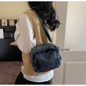 Dettaglio borsa a tracolla in denim lavato vintage con patch logo in pelle e strati di zip