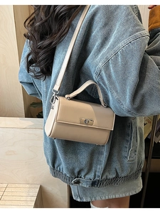 Detail of cream mini square handbag showing silver twist lock and polished handle texture