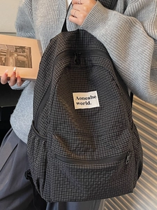 Minimalist black and white checkered canvas backpack with a large main compartment