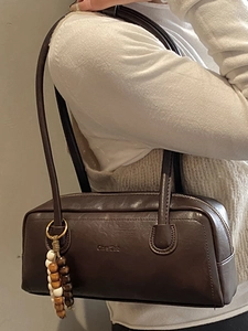 Deep coffee leather underarm bag with beaded pendant shown as worn on shoulder