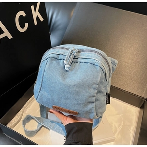 Dettaglio della borsa in denim azzurro che mostra la trama del tessuto e il logo in pelle