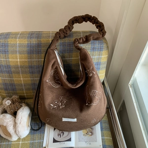 Detail of brown wool blend tote bag featuring white embroidery and ruffled shoulder strap
