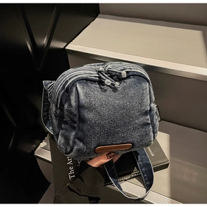 Dettaglio della borsa a tracolla in denim lavato con doppia cerniera e logo in pelle