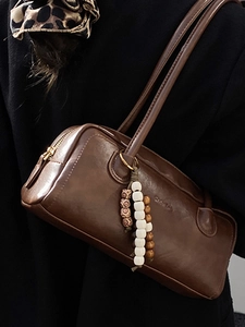 Vintage brown leather underarm bag with decorative beaded tassel and gold hardware detail