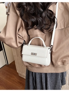 White faux leather mini crossbody bag with silver twist lock shown on a female model